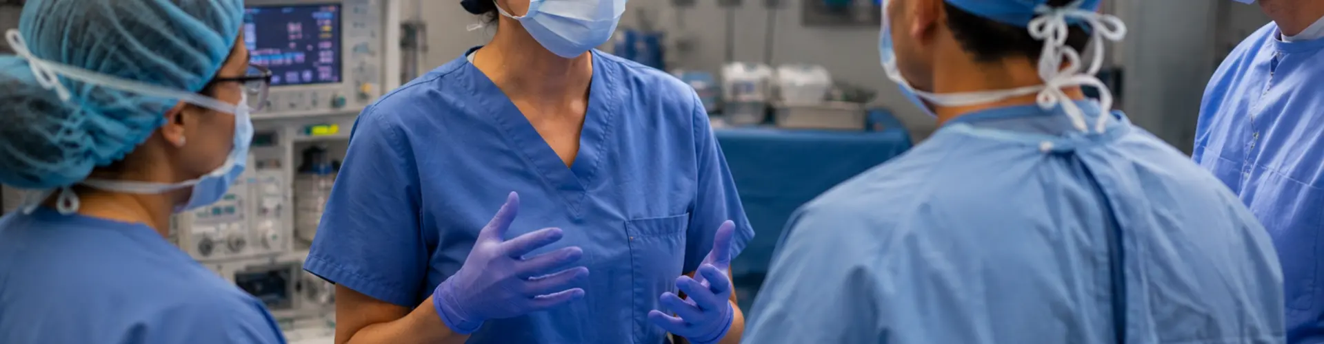 CRNA leading a collaborative preoperative discussion with surgeons and operating room staff in a modern surgical suite.