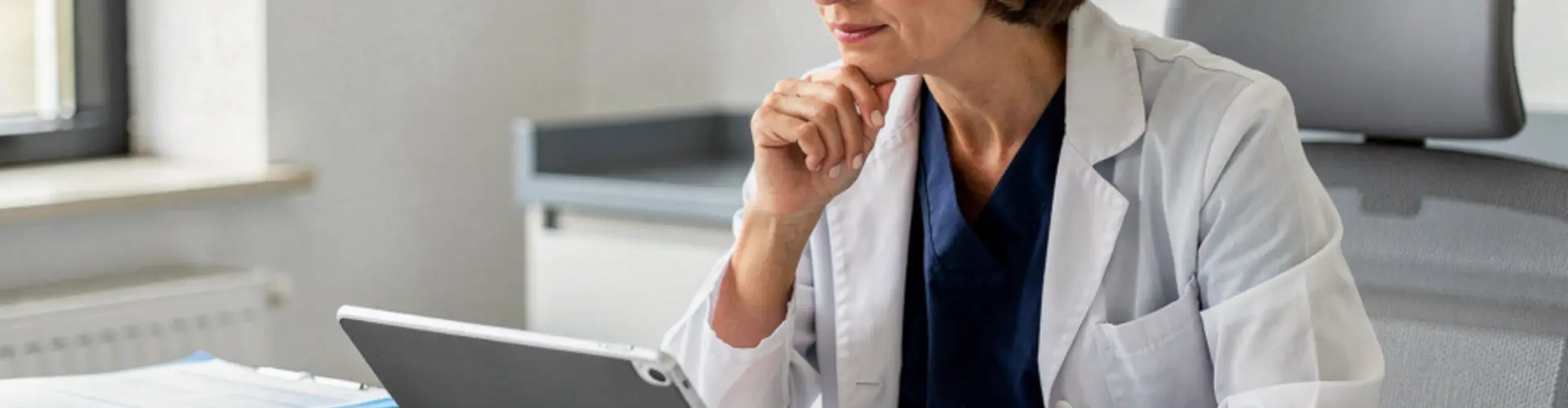 Experienced nurse practitioner reviewing clinical information on a tablet, representing the analytical, legal, and systems-level knowledge that contributes to effective advanced practice care.